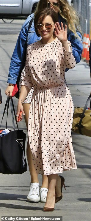 Beaming: Emilia flashed a big grin and a wave as she headed in through the stage door